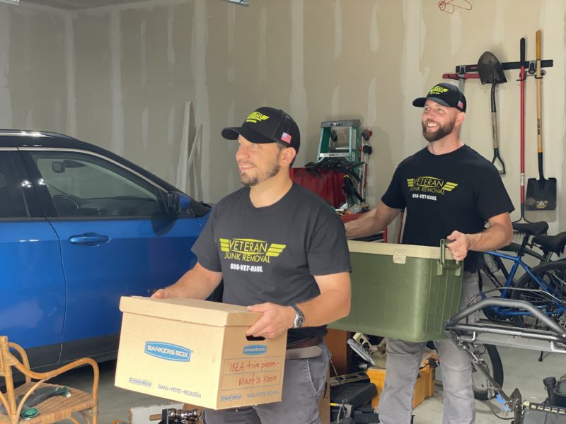 Veteran Junk Removal experts carrying boxes of junk out of garage