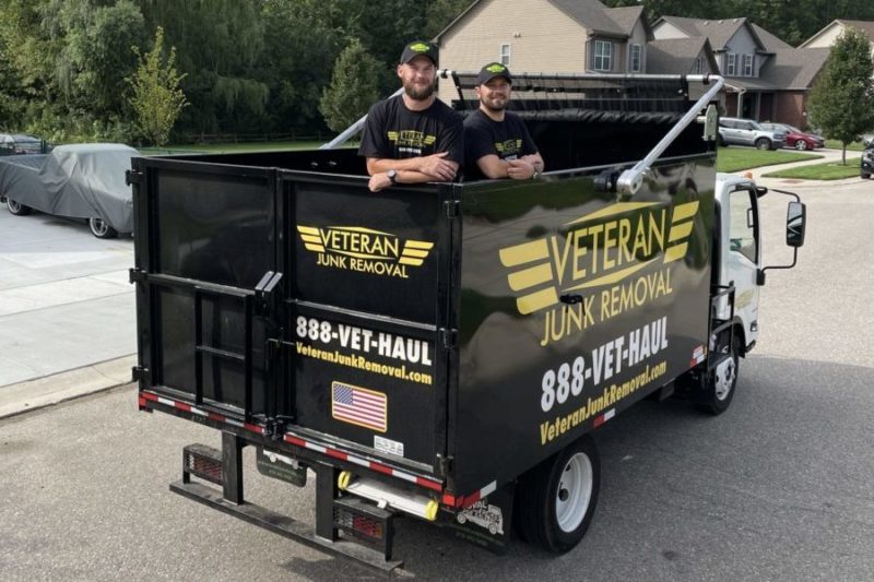 veteran junk removal pros smiling in back of junk truck