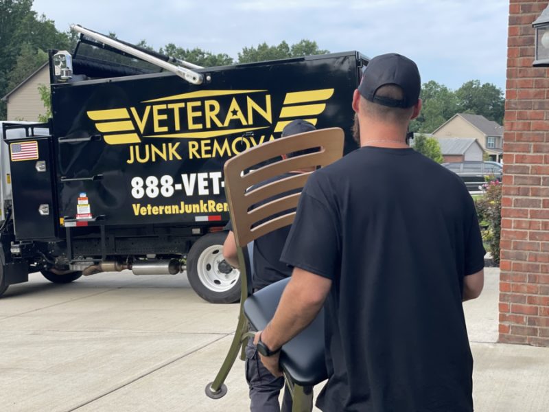 junk removal pro carrying chair to veteran junk removal truck