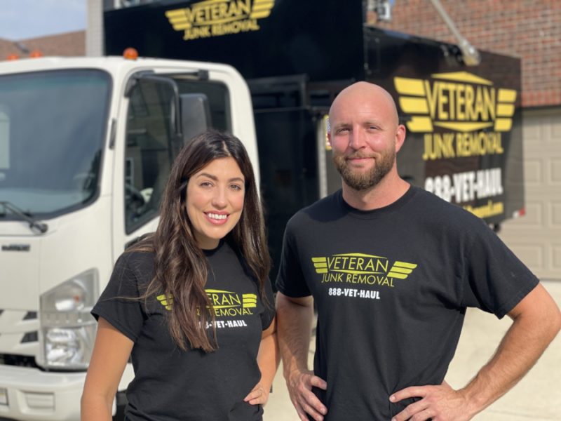veteran junk removal pros smiling in front of junk truck